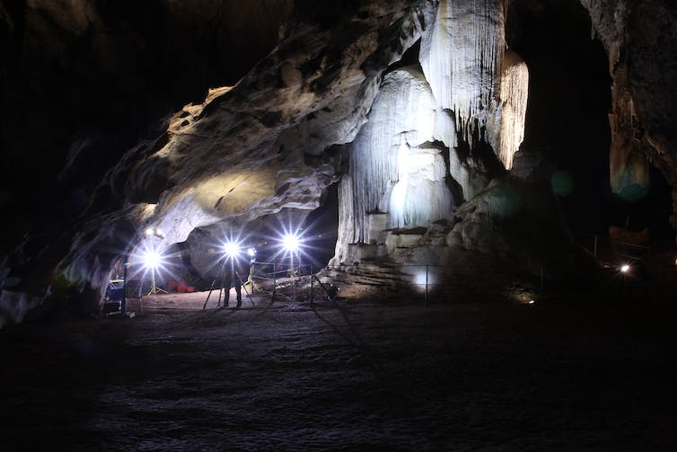 Interior of a cave chamber, with a large stalagmite reaching from the floor to the roof